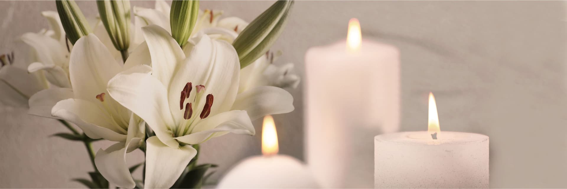 Elegant white lilies in a serene setting, complemented by glowing candles, create a calming ambiance.
